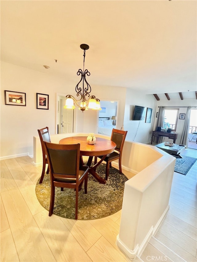 dining space with light hardwood / wood-style floors, a chandelier, and beamed ceiling