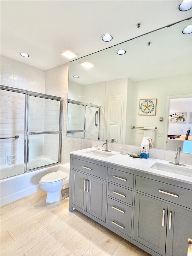 full bathroom featuring vanity, toilet, tile walls, and shower / bath combination with glass door