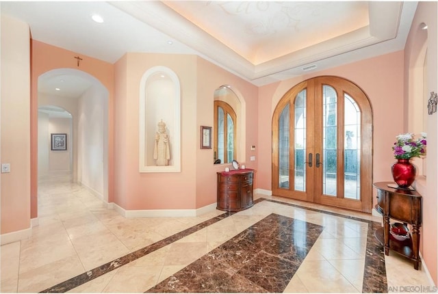 foyer featuring french doors and a raised ceiling