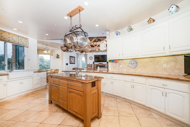 kitchen featuring white cabinetry, light stone countertops, sink, and an island with sink