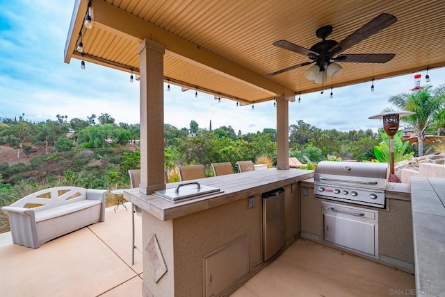 view of patio / terrace with ceiling fan, a grill, and exterior kitchen