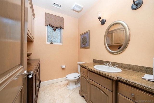 bathroom with toilet, vanity, and tile patterned floors