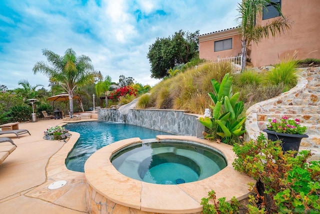 view of pool with a patio area, pool water feature, and an in ground hot tub