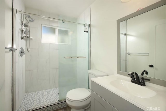 bathroom featuring a shower with door, vanity, and toilet