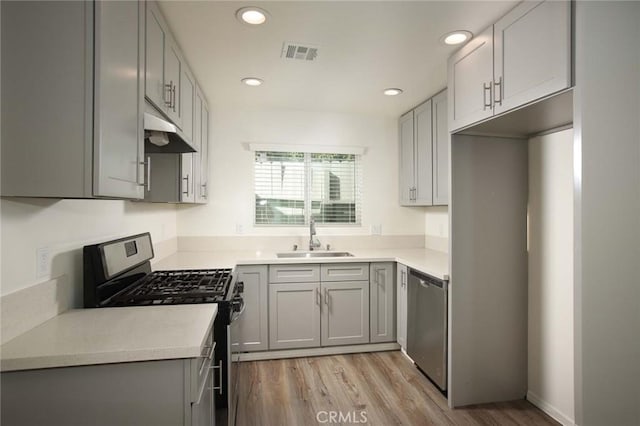 kitchen with stainless steel appliances, gray cabinets, sink, and light hardwood / wood-style flooring