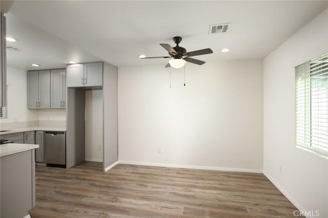 kitchen featuring ceiling fan, hardwood / wood-style flooring, gray cabinets, and dishwasher