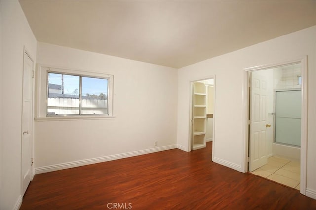 unfurnished bedroom with a spacious closet and wood-type flooring