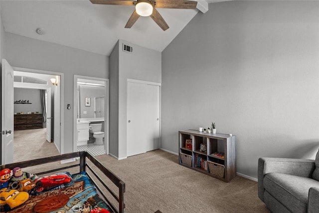 bedroom featuring ceiling fan, lofted ceiling with beams, ensuite bath, and light colored carpet