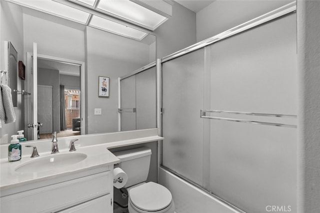 full bathroom featuring vanity, combined bath / shower with glass door, and toilet