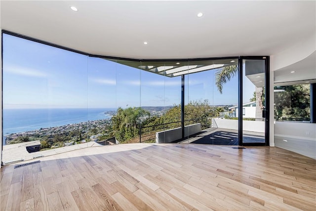 interior space featuring floor to ceiling windows, a water view, and light hardwood / wood-style flooring