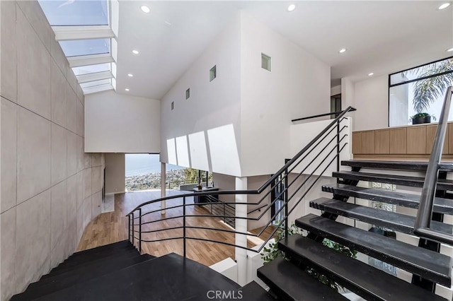 staircase featuring hardwood / wood-style flooring, plenty of natural light, and a high ceiling