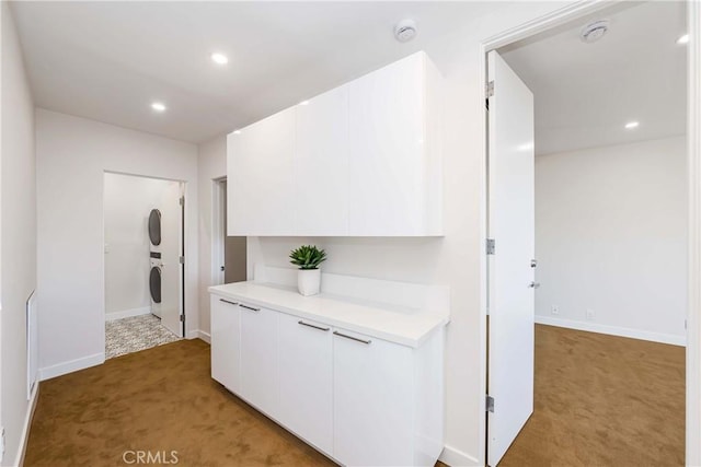 corridor with stacked washer and clothes dryer and carpet