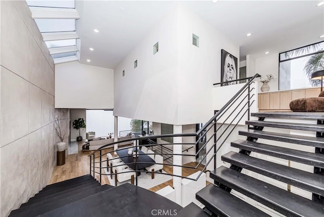 stairs with wood-type flooring, high vaulted ceiling, and a wealth of natural light