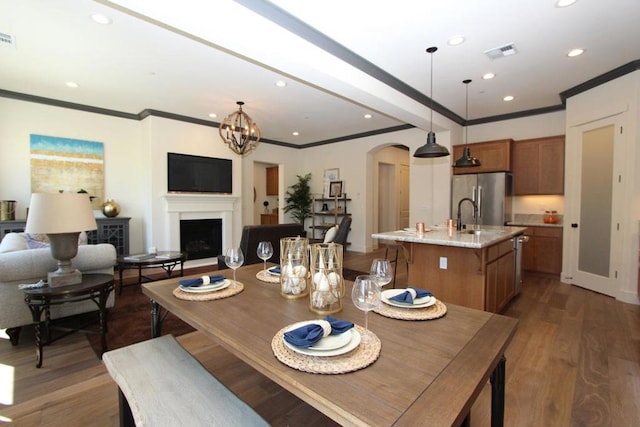 dining area with crown molding, dark hardwood / wood-style floors, sink, and a notable chandelier