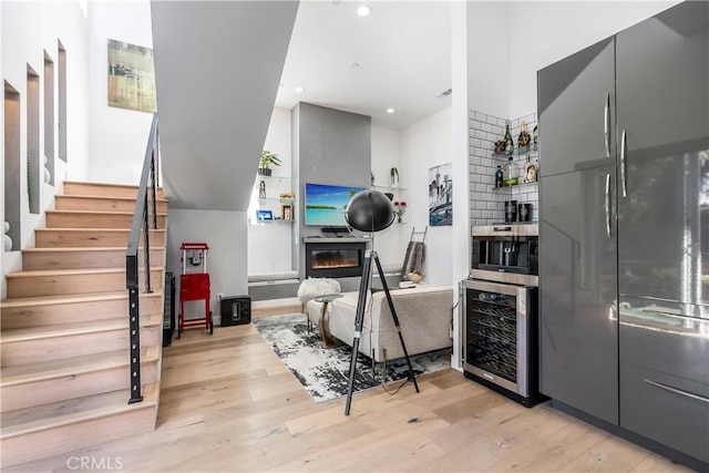 kitchen with stainless steel built in refrigerator, beverage cooler, gray cabinets, and light hardwood / wood-style flooring