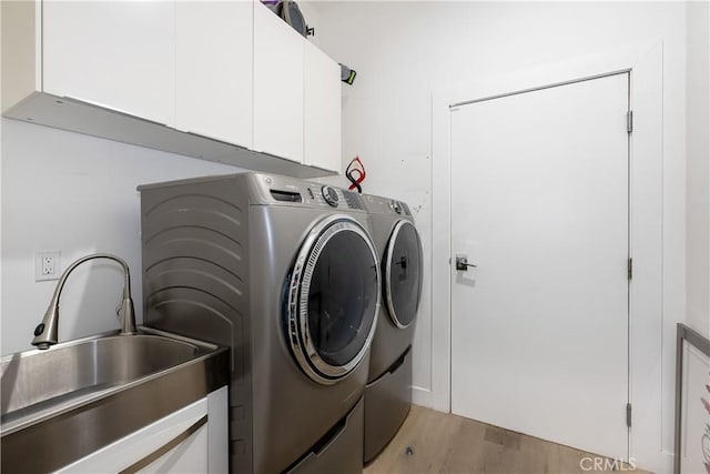 clothes washing area with cabinets, separate washer and dryer, sink, and light wood-type flooring