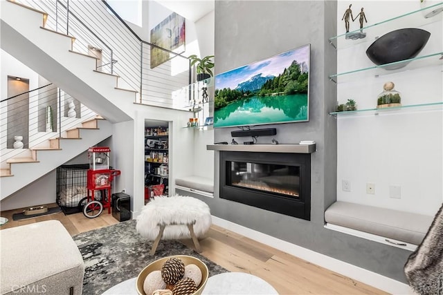 living room with a towering ceiling and light hardwood / wood-style flooring