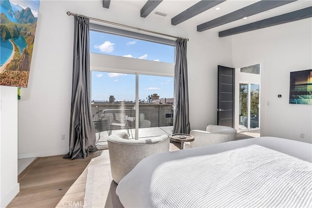 bedroom with a towering ceiling, beam ceiling, light wood-type flooring, and access to outside