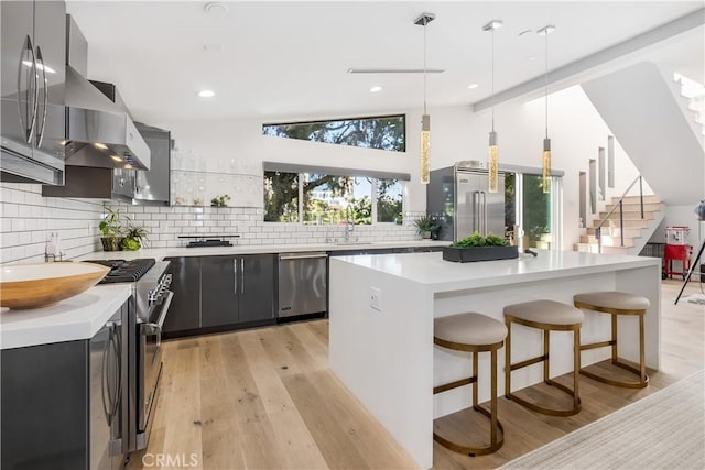 kitchen with pendant lighting, vaulted ceiling, light hardwood / wood-style floors, and high quality appliances