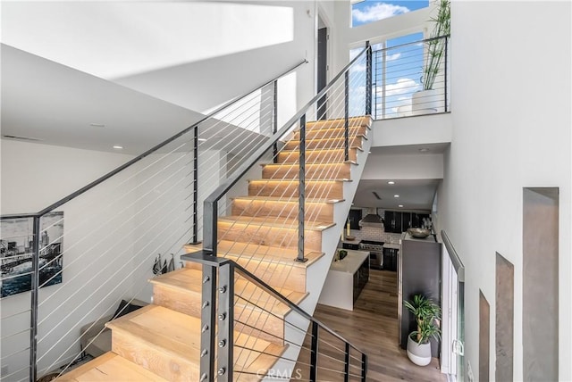 staircase featuring hardwood / wood-style flooring and a high ceiling