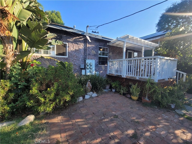 back of property featuring a wooden deck, a patio, and a pergola