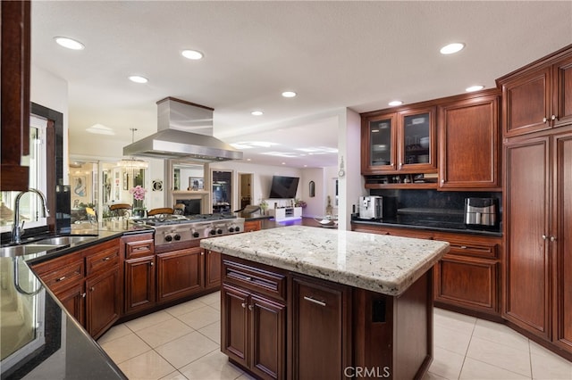 kitchen featuring island exhaust hood, a kitchen island, stainless steel gas stovetop, light stone countertops, and sink