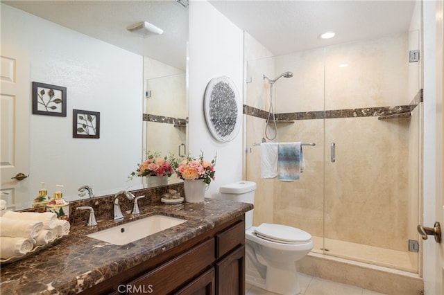 bathroom with a shower with door, vanity, toilet, and tile patterned flooring