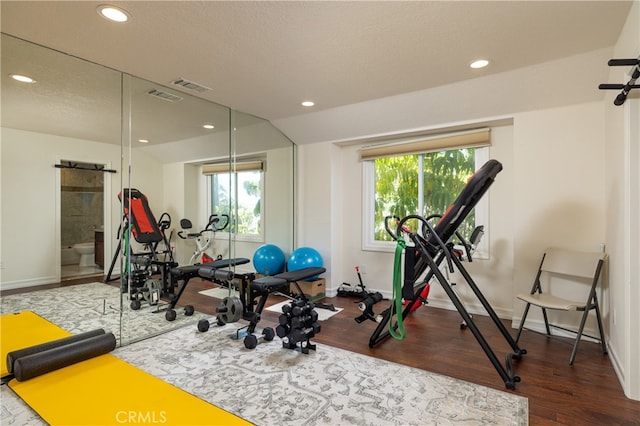 exercise room featuring a textured ceiling, a barn door, and wood-type flooring