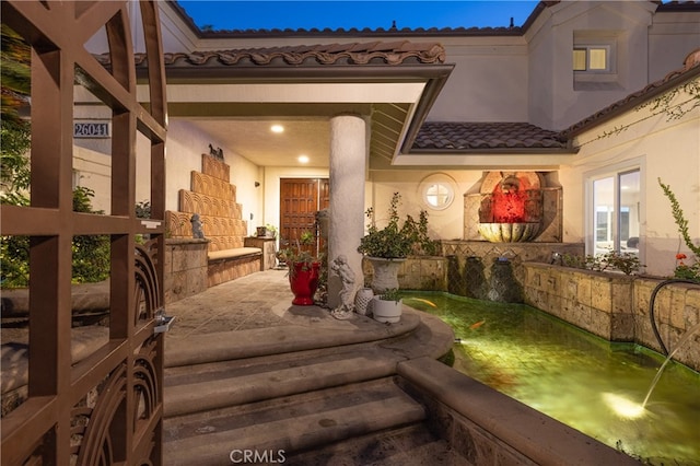 property entrance with an outdoor fireplace and a patio