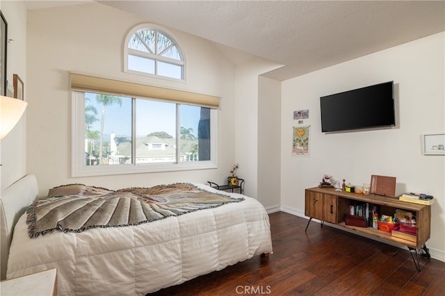 bedroom with a textured ceiling, lofted ceiling, and dark hardwood / wood-style floors