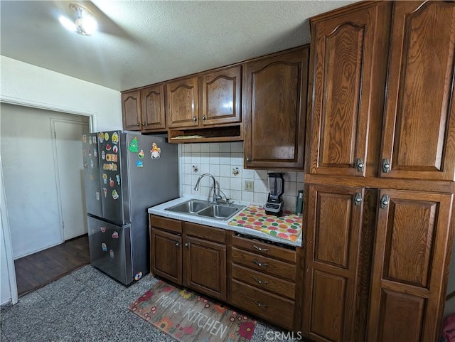 kitchen featuring tasteful backsplash, stainless steel refrigerator, and sink