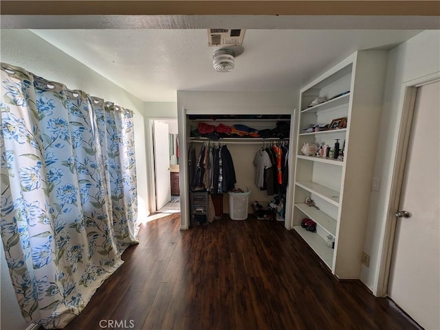 walk in closet with dark hardwood / wood-style flooring