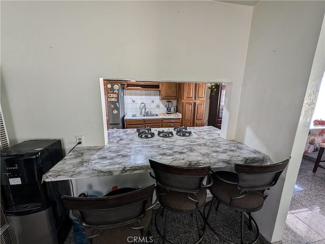 kitchen featuring a kitchen breakfast bar, kitchen peninsula, white gas stovetop, and sink