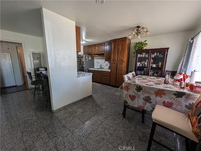 kitchen featuring decorative backsplash, stainless steel fridge, sink, and a textured ceiling