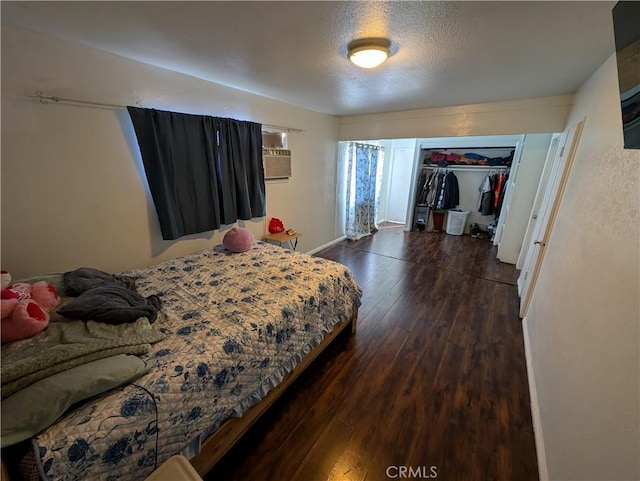 bedroom featuring an AC wall unit, a closet, dark hardwood / wood-style flooring, and a textured ceiling