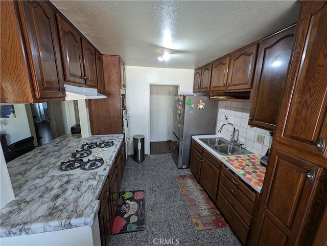 kitchen featuring sink, white gas cooktop, backsplash, stainless steel fridge, and a textured ceiling