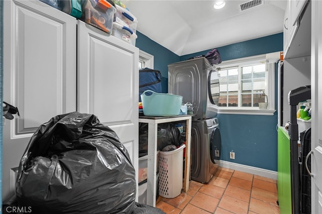 washroom with stacked washer and dryer and light tile patterned floors