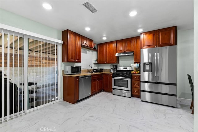 kitchen with stainless steel appliances, light stone counters, and sink