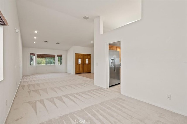 unfurnished living room featuring light carpet and vaulted ceiling