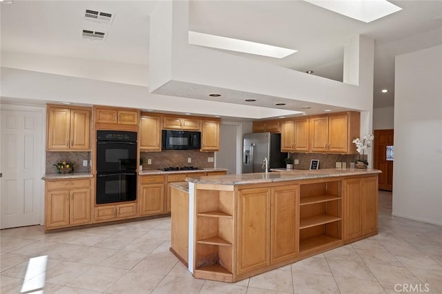 kitchen with a skylight, tasteful backsplash, a center island, and black appliances