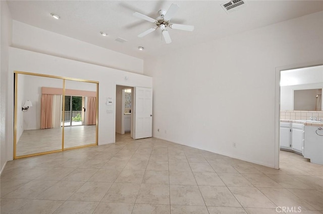 unfurnished bedroom featuring connected bathroom, light tile patterned floors, a closet, and ceiling fan