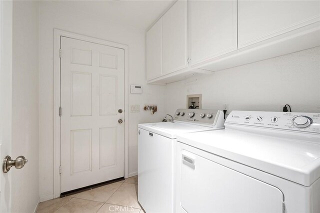 washroom featuring light tile patterned floors, washing machine and dryer, and cabinets