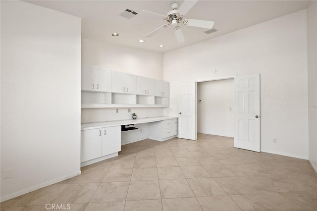 unfurnished office featuring high vaulted ceiling, built in desk, ceiling fan, and light tile patterned floors