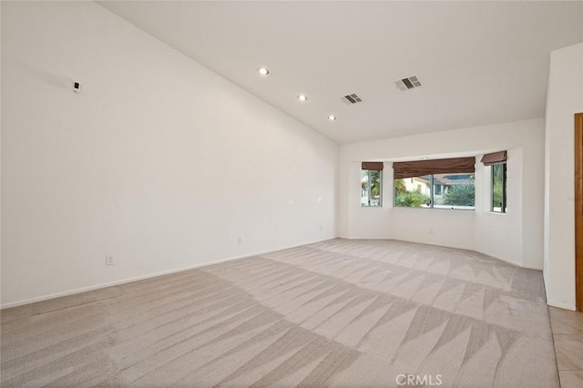 spare room featuring light colored carpet and vaulted ceiling