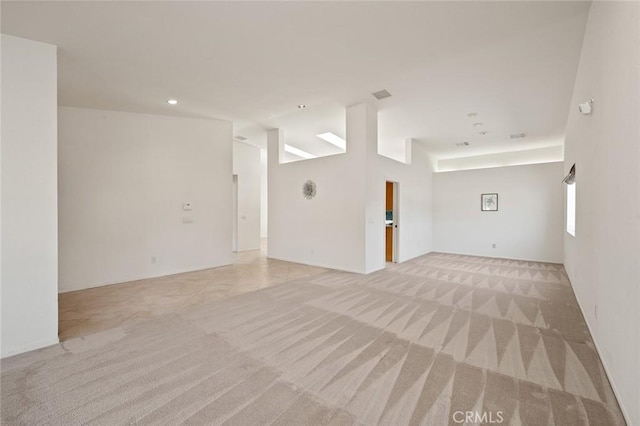 spare room with light colored carpet and lofted ceiling