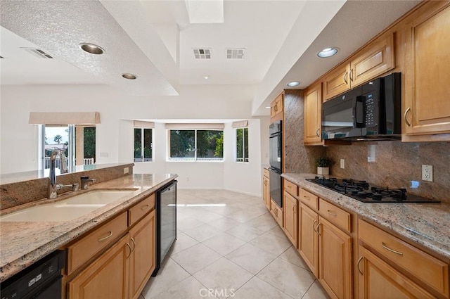 kitchen featuring sink, backsplash, light tile patterned floors, light stone counters, and black appliances