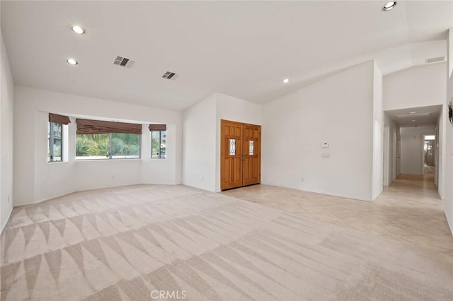 unfurnished living room featuring high vaulted ceiling and light carpet