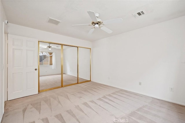 unfurnished bedroom featuring light colored carpet, ceiling fan, and a closet