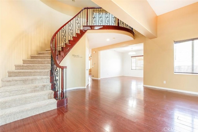 stairs with plenty of natural light, hardwood / wood-style floors, and a chandelier