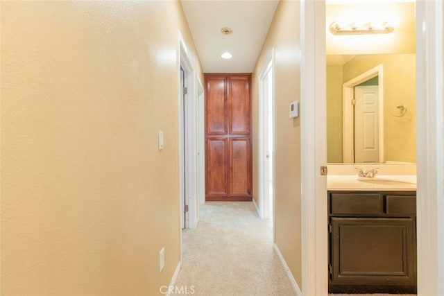 hallway featuring light carpet and sink